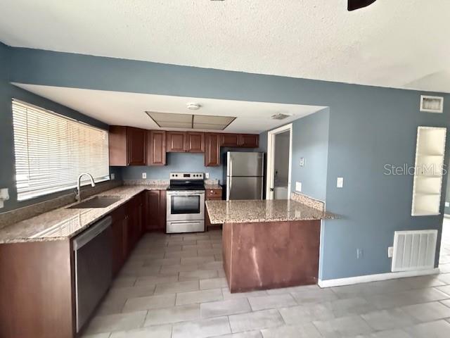 5423 Brookswood Way Unit 801, Orlando, FL 32808 - kitchen with appliances with stainless steel finishes, light stone countertops, and a peninsula