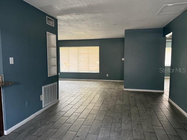 5423 Brookswood Way Unit 801, Orlando, FL 32808 - empty room featuring healthy amount of natural light, a textured ceiling, and wood finished floors