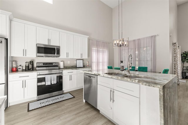 2313 Duncan Trl, Clermont, FL 34714 - kitchen with stainless steel appliances, a high ceiling, a chandelier, white cabinets, and a kitchen island with sink