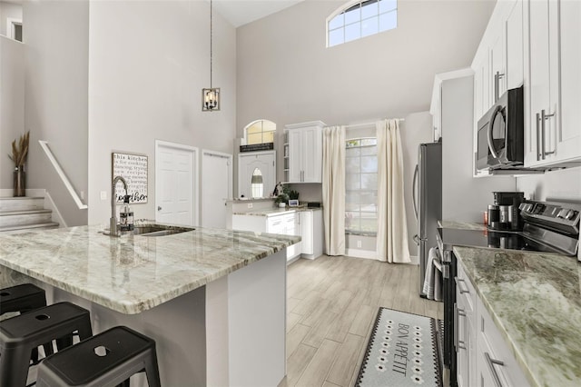 2313 Duncan Trl, Clermont, FL 34714 - kitchen with appliances with stainless steel finishes, a high ceiling, a breakfast bar area, white cabinets, and light stone countertops
