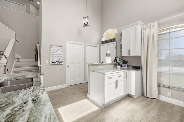 2313 Duncan Trl, Clermont, FL 34714 - kitchen with white cabinets, plenty of natural light, a high ceiling, light stone counters, and light wood-style floors