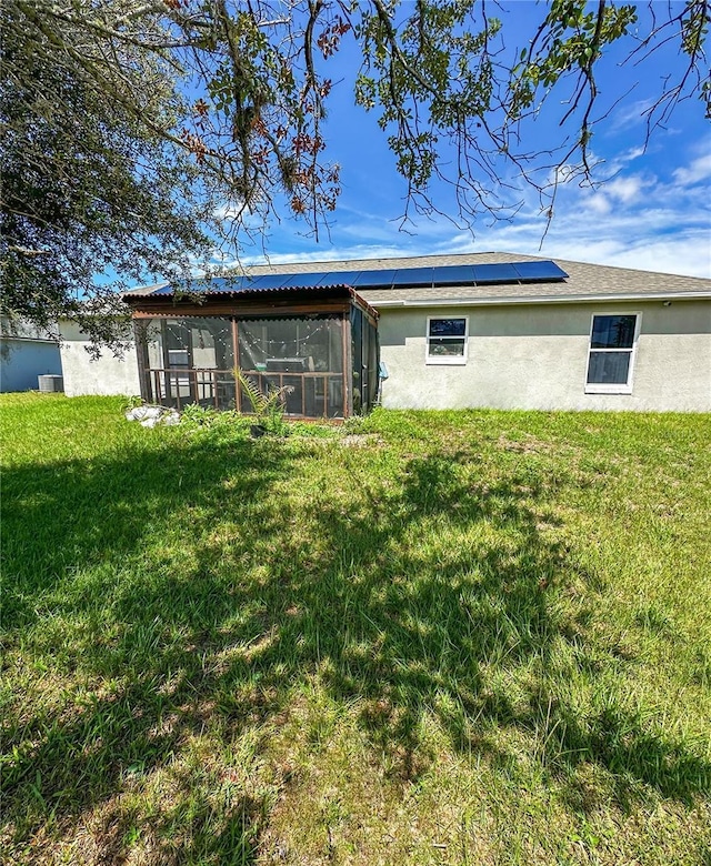 2333 Ainsworth Ave, Deltona, FL 32738 - back of house featuring a sunroom, solar panels, stucco siding, and a lawn