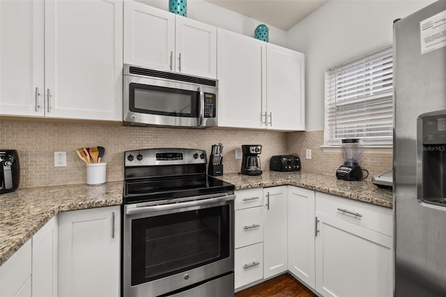 5372 Diplomat Ct Unit 108, Kissimmee, FL 34746 - kitchen featuring appliances with stainless steel finishes, white cabinetry, tasteful backsplash, and light stone countertops