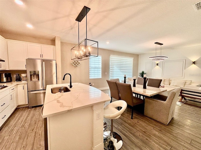1399 Greenfield Loop, Kissimmee, FL 34747 - kitchen with stainless steel fridge, a kitchen island with sink, light wood-style floors, white cabinets, and recessed lighting