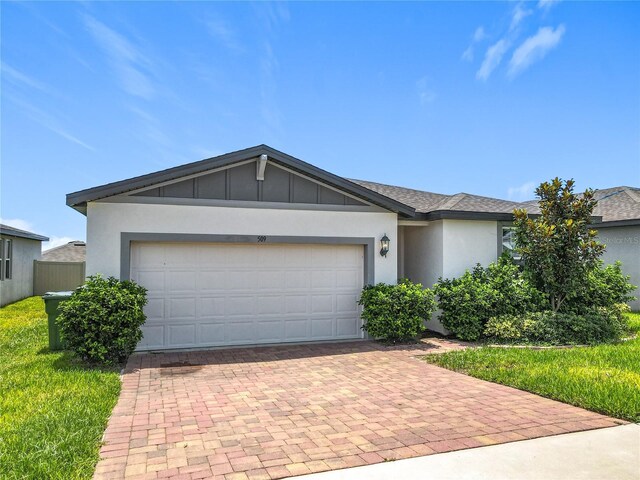 509 Mckenna Dr, Winter Haven, FL 33881 - view of front of home featuring decorative driveway, board and batten siding, an attached garage, stucco siding, and a front yard