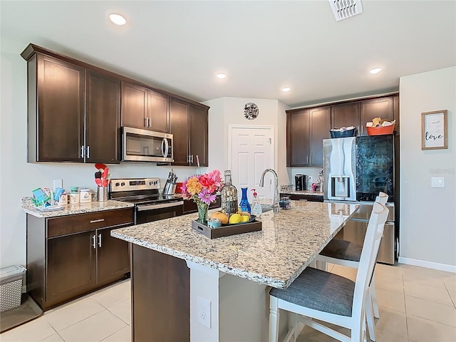 509 Mckenna Dr, Winter Haven, FL 33881 - kitchen with appliances with stainless steel finishes, dark brown cabinets, light tile patterned floors, a breakfast bar, and recessed lighting