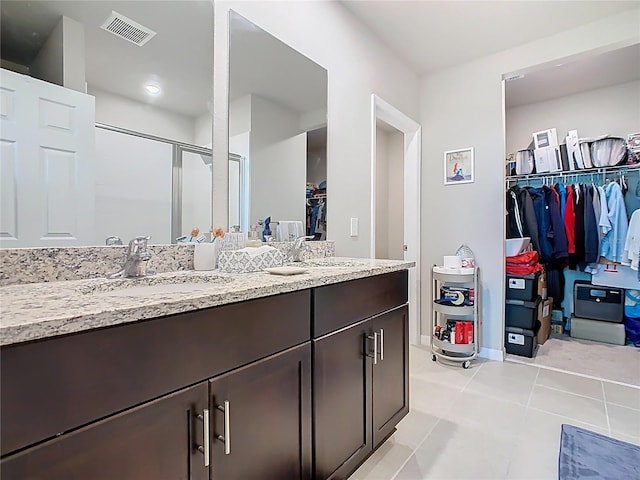 509 Mckenna Dr, Winter Haven, FL 33881 - bathroom featuring a walk in closet, double vanity, a stall shower, and tile patterned flooring