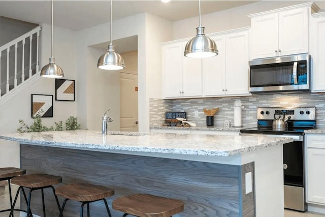 4254 Lana Ave, Davenport, FL 33897 - kitchen featuring appliances with stainless steel finishes, a kitchen breakfast bar, backsplash, light stone counters, and white cabinets