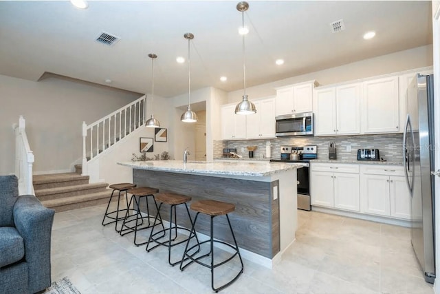 4254 Lana Ave, Davenport, FL 33897 - kitchen featuring appliances with stainless steel finishes, open floor plan, decorative backsplash, white cabinetry, and a breakfast bar area