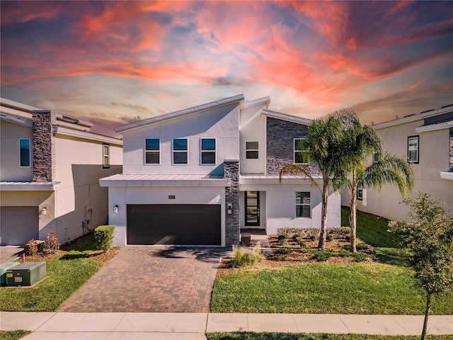 681 Pebble Beach Dr, Davenport, FL 33896 - contemporary home with stucco siding, decorative driveway, stone siding, a garage, and a metal roof