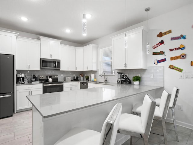 681 Pebble Beach Dr, Davenport, FL 33896 - kitchen with stainless steel appliances, a peninsula, a kitchen bar, white cabinetry, and recessed lighting