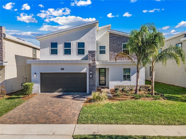 681 Pebble Beach Dr, Davenport, FL 33896 - view of front of home with stone siding, decorative driveway, stucco siding, a garage, and a front lawn