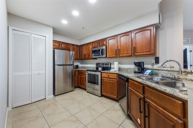 8774 Worldquest Blvd Unit 7404, Orlando, FL 32821 - kitchen with appliances with stainless steel finishes, light tile patterned floors, brown cabinetry, recessed lighting, and light stone countertops