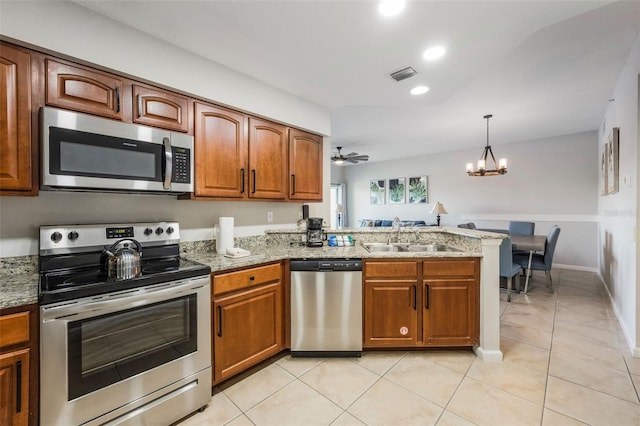 8774 Worldquest Blvd Unit 7404, Orlando, FL 32821 - kitchen with stainless steel appliances, brown cabinetry, a peninsula, light stone counters, and recessed lighting