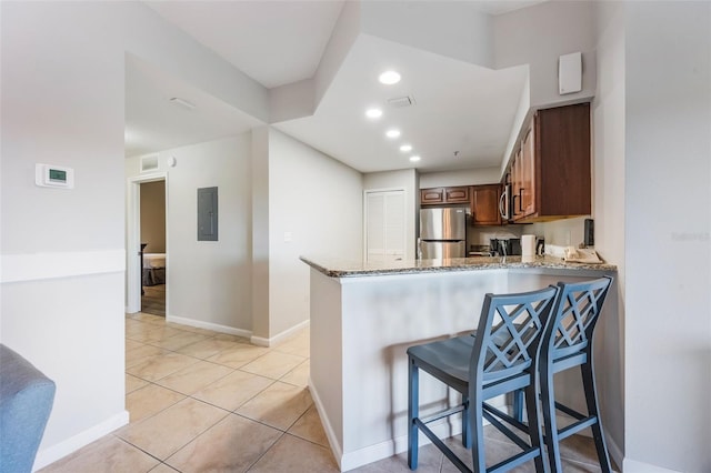 8774 Worldquest Blvd Unit 7404, Orlando, FL 32821 - kitchen with freestanding refrigerator, light stone countertops, electric panel, a kitchen bar, and a peninsula