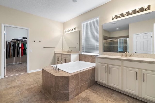 1817 Westerham Ave, Saint Cloud, FL 34771 - bathroom featuring a stall shower, two vanities, a garden tub, a spacious closet, and tile patterned floors