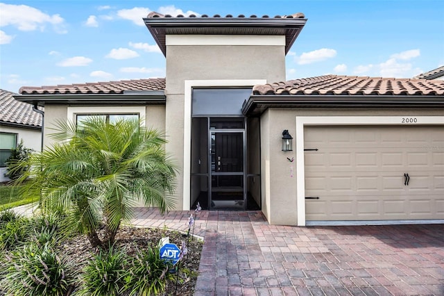 2000 Goblet Cove St, Kissimmee, FL 34746 - view of exterior entry featuring a tiled roof, stucco siding, a garage, and decorative driveway