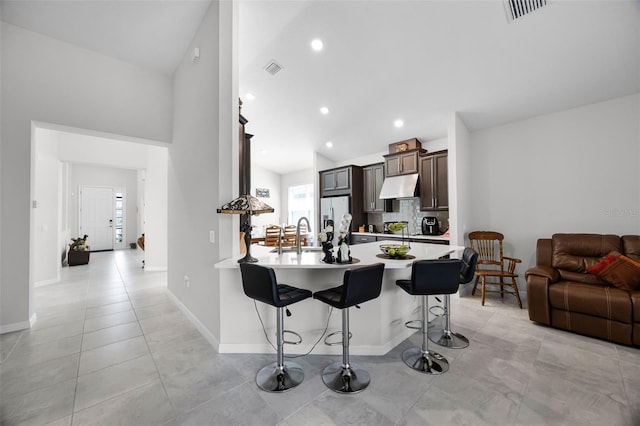 2000 Goblet Cove St, Kissimmee, FL 34746 - kitchen with under cabinet range hood, stainless steel refrigerator with ice dispenser, a breakfast bar area, light countertops, and a peninsula