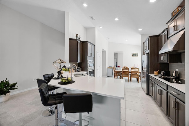 2000 Goblet Cove St, Kissimmee, FL 34746 - kitchen with under cabinet range hood, stainless steel appliances, light countertops, dark brown cabinetry, and recessed lighting