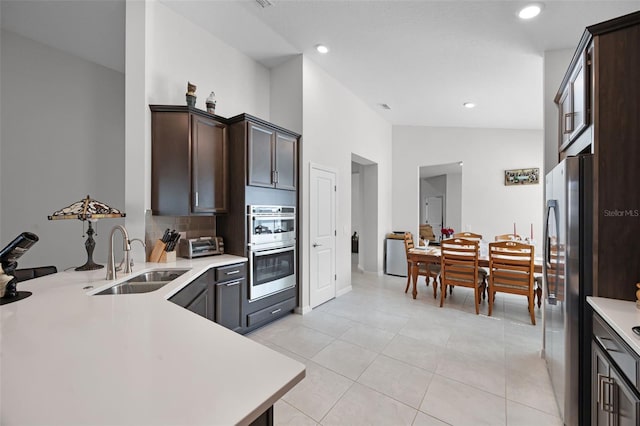 2000 Goblet Cove St, Kissimmee, FL 34746 - kitchen featuring appliances with stainless steel finishes, light countertops, dark brown cabinetry, tasteful backsplash, and vaulted ceiling