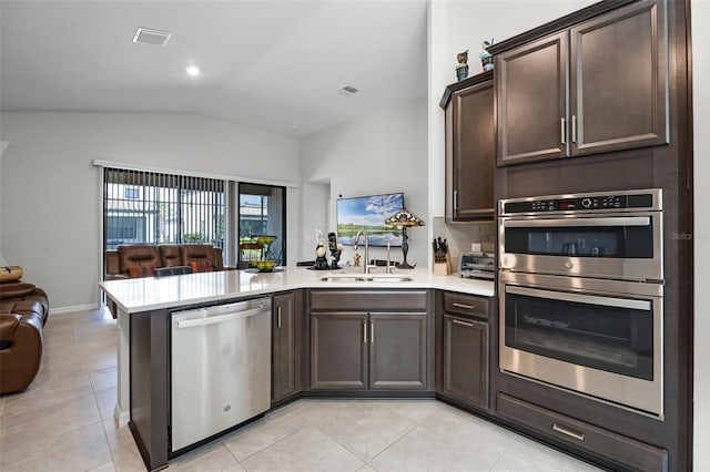 2000 Goblet Cove St, Kissimmee, FL 34746 - kitchen with stainless steel appliances, open floor plan, a peninsula, vaulted ceiling, and dark brown cabinets