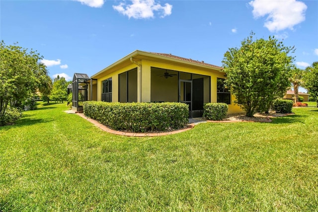 3390 Fallbrook Dr, Kissimmee, FL 34759 - back of property featuring a yard, a ceiling fan, and stucco siding