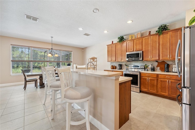 143 Tiger Lily Ct, Davenport, FL 33837 - kitchen with stainless steel appliances, light countertops, brown cabinets, backsplash, and recessed lighting
