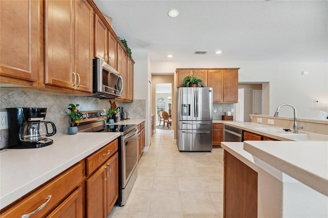 143 Tiger Lily Ct, Davenport, FL 33837 - kitchen with stainless steel appliances, brown cabinetry, light countertops, and recessed lighting