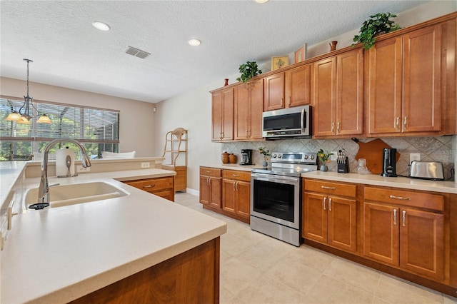 143 Tiger Lily Ct, Davenport, FL 33837 - kitchen featuring stainless steel appliances, brown cabinets, light countertops, backsplash, and a textured ceiling
