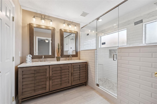 143 Tiger Lily Ct, Davenport, FL 33837 - bathroom with a shower stall, double vanity, a ceiling fan, and a textured ceiling