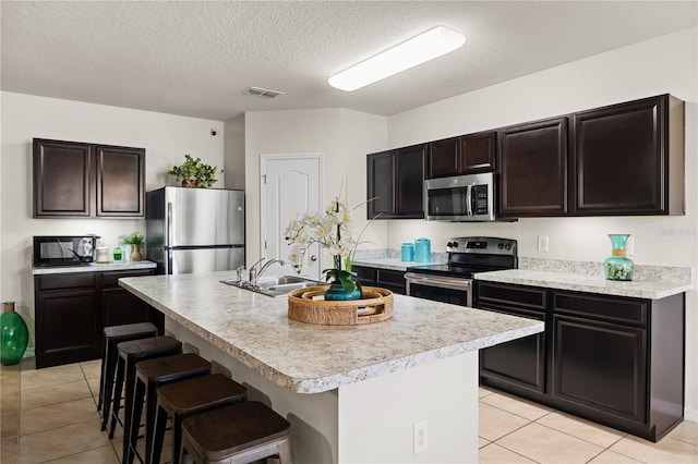 555 Lucerne Blvd, Winter Haven, FL 33881 - kitchen with appliances with stainless steel finishes, light tile patterned floors, light countertops, a breakfast bar area, and a textured ceiling