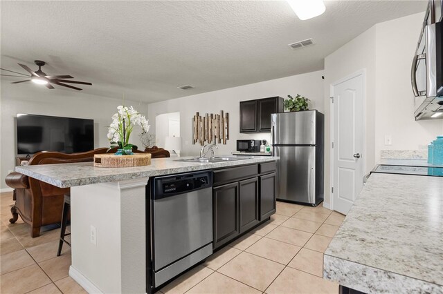 555 Lucerne Blvd, Winter Haven, FL 33881 - kitchen with appliances with stainless steel finishes, light tile patterned floors, a kitchen island with sink, light countertops, and a textured ceiling