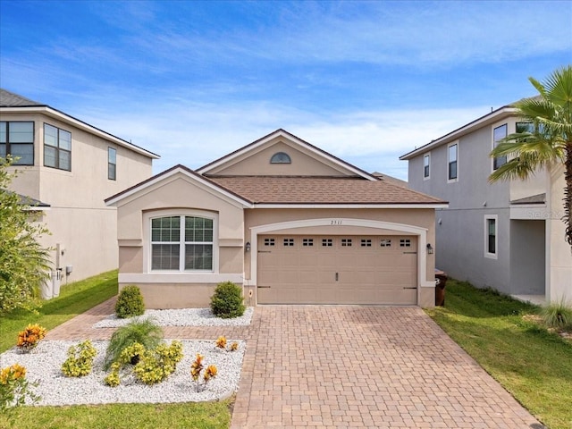 2511 Nouveau Way, Kissimmee, FL 34741 - view of front facade with decorative driveway, a garage, stucco siding, a shingled roof, and a front lawn