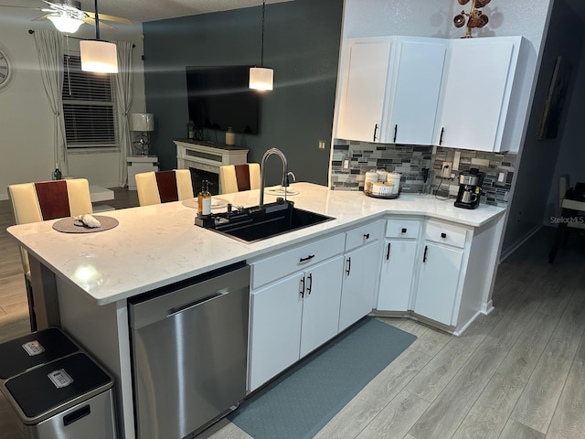 6003 Live Oak Dr, Winter Haven, FL 33880 - kitchen with stainless steel dishwasher, light wood-style floors, a peninsula, decorative backsplash, and white cabinetry