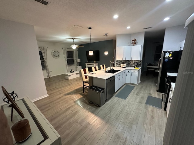 6003 Live Oak Dr, Winter Haven, FL 33880 - kitchen featuring a peninsula, appliances with stainless steel finishes, a kitchen breakfast bar, ceiling fan, and light wood finished floors