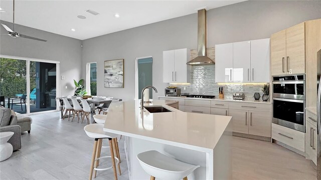 7551 Excitement Dr, Reunion, FL 34747 - kitchen with double oven, wall chimney exhaust hood, decorative backsplash, a ceiling fan, and light countertops