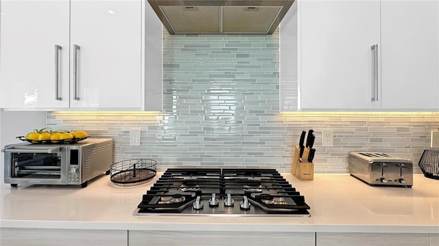 7551 Excitement Dr, Reunion, FL 34747 - kitchen with range hood, stainless steel gas stovetop, white cabinetry, tasteful backsplash, and light countertops