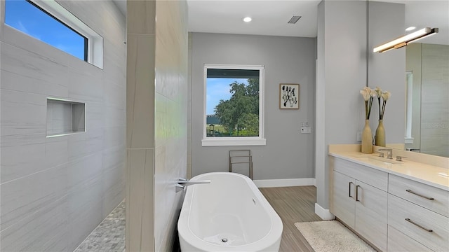 7551 Excitement Dr, Reunion, FL 34747 - bathroom featuring a soaking tub, vanity, wood finished floors, tiled shower, and recessed lighting