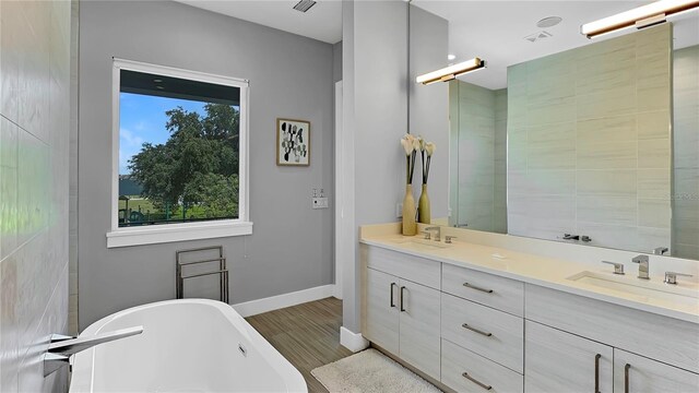 7551 Excitement Dr, Reunion, FL 34747 - full bathroom with double vanity, a soaking tub, and wood finished floors