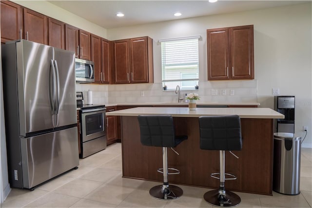 2712 Creekmore Ct, Kissimmee, FL 34746 - kitchen with appliances with stainless steel finishes, a center island, backsplash, light countertops, and a breakfast bar area