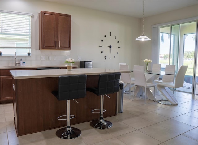 2712 Creekmore Ct, Kissimmee, FL 34746 - kitchen featuring light countertops, a kitchen island, a kitchen breakfast bar, hanging light fixtures, and decorative backsplash