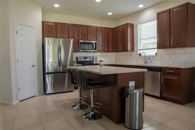2712 Creekmore Ct, Kissimmee, FL 34746 - kitchen with appliances with stainless steel finishes, a center island, a kitchen breakfast bar, light countertops, and decorative backsplash