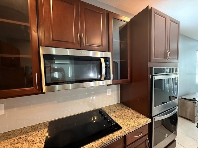 16856 Meadows St, Clermont, FL 34714 - kitchen with appliances with stainless steel finishes, decorative backsplash, light stone countertops, and light tile patterned flooring