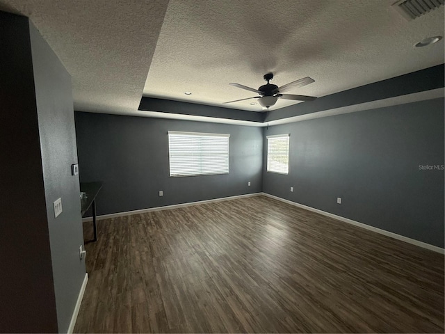 16856 Meadows St, Clermont, FL 34714 - unfurnished room with a textured ceiling, dark wood-style flooring, ceiling fan, and a tray ceiling