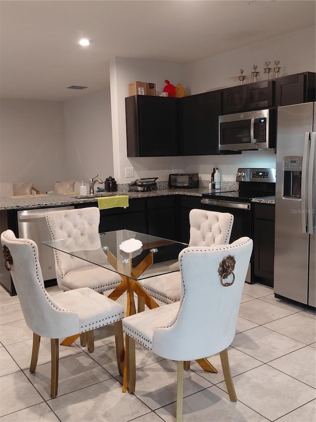 1509 Majestic, Winter Haven, FL 33880 - kitchen featuring stainless steel appliances, light tile patterned floors, dark cabinetry, light stone counters, and recessed lighting