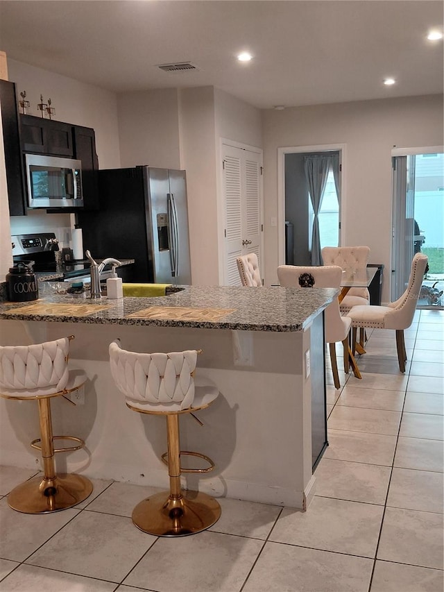1509 Majestic, Winter Haven, FL 33880 - kitchen featuring stainless steel appliances, light stone counters, a kitchen bar, light tile patterned floors, and recessed lighting
