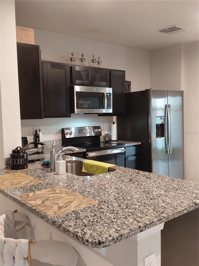 1509 Majestic, Winter Haven, FL 33880 - kitchen with appliances with stainless steel finishes, a peninsula, a kitchen breakfast bar, and light stone countertops