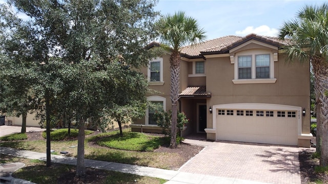 2183 Tripoli Ct, Kissimmee, FL 34747 - mediterranean / spanish house with stucco siding, a tiled roof, decorative driveway, and an attached garage