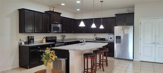 2183 Tripoli Ct, Kissimmee, FL 34747 - kitchen with appliances with stainless steel finishes, light tile patterned flooring, a breakfast bar area, a center island with sink, and pendant lighting