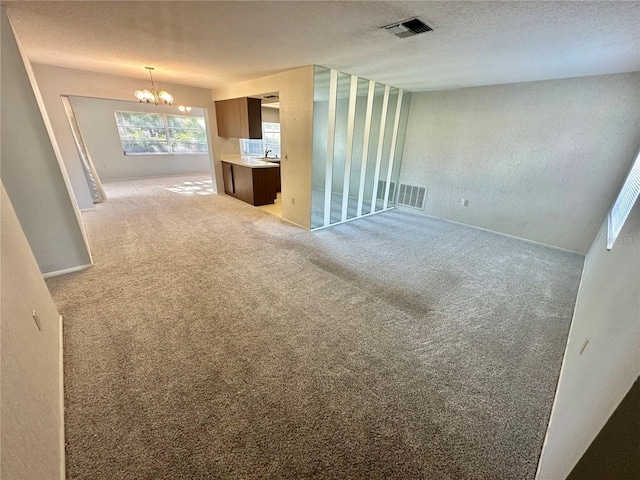 13102 Pembrook Ct, Hudson, FL 34667 - unfurnished living room featuring a chandelier, light carpet, and a textured ceiling